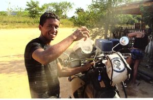 A Brazilian local helps Freund fill his gas tank by simply unzipping the Fandango Pro Tank Bag from the included harness that is securely strapped to his Kawasaki KLR 650